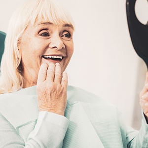 a dentures patient smiling in the mirror
