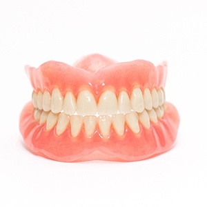 Full set of glistening dentures on a white background