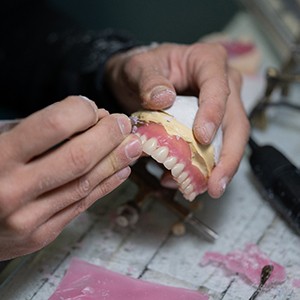 Lab tech shaping acrylic gums on dentures