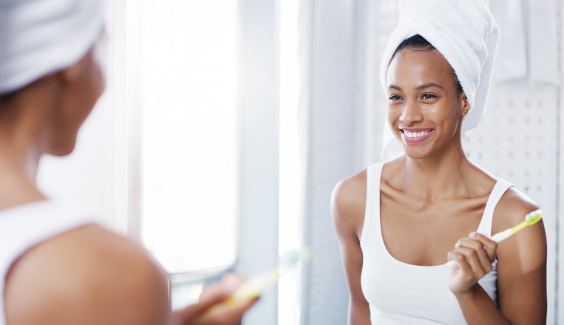 woman brushing her teeth in the mirror