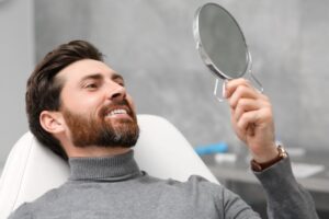 Male dental patient smiling in mirror